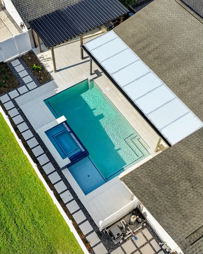 Custom pool with a water cascade and navy waterline tile built by Pool Perfection in Seminole