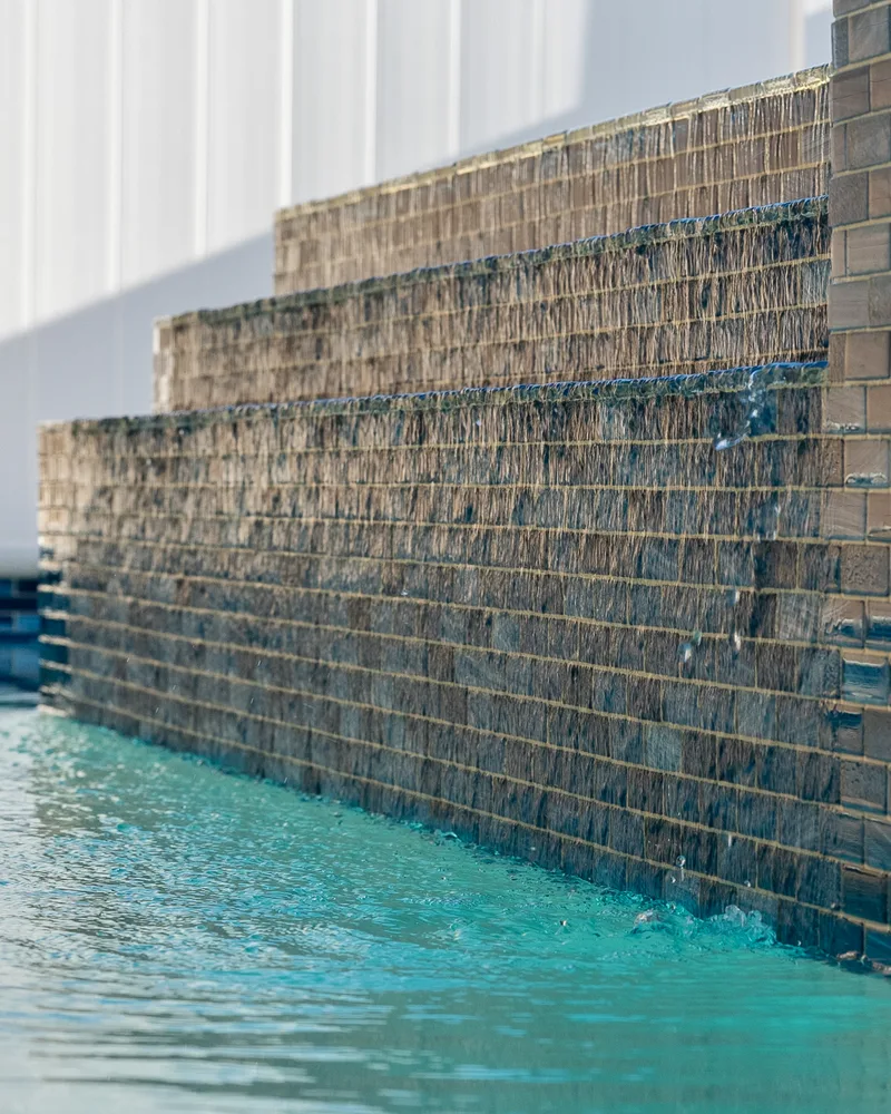 Custom pool with a water cascade and navy waterline tile built by Pool Perfection in Seminole