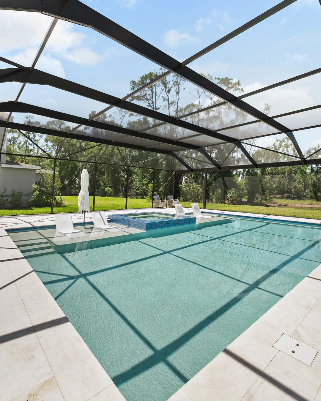 Wesley Chapel custom pool under a screen enclosure with a raised spa and sandblasted marble deck